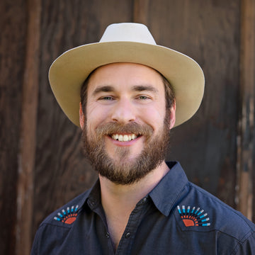 Adam headshot wearing bone colored hat and black shirt